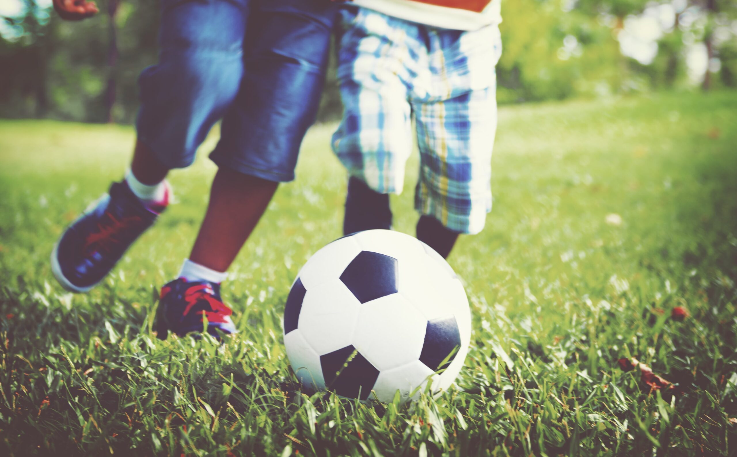 kids playing football grass min scaled 1